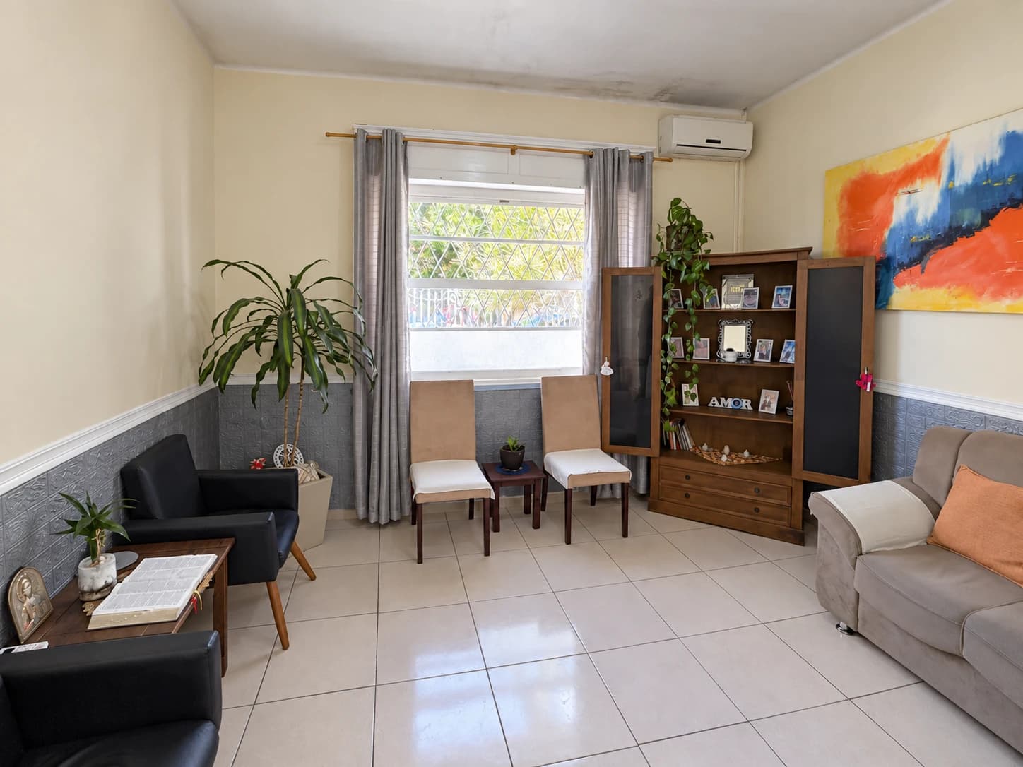 Sala de estar com poltronas, cadeiras, estante e luz natural